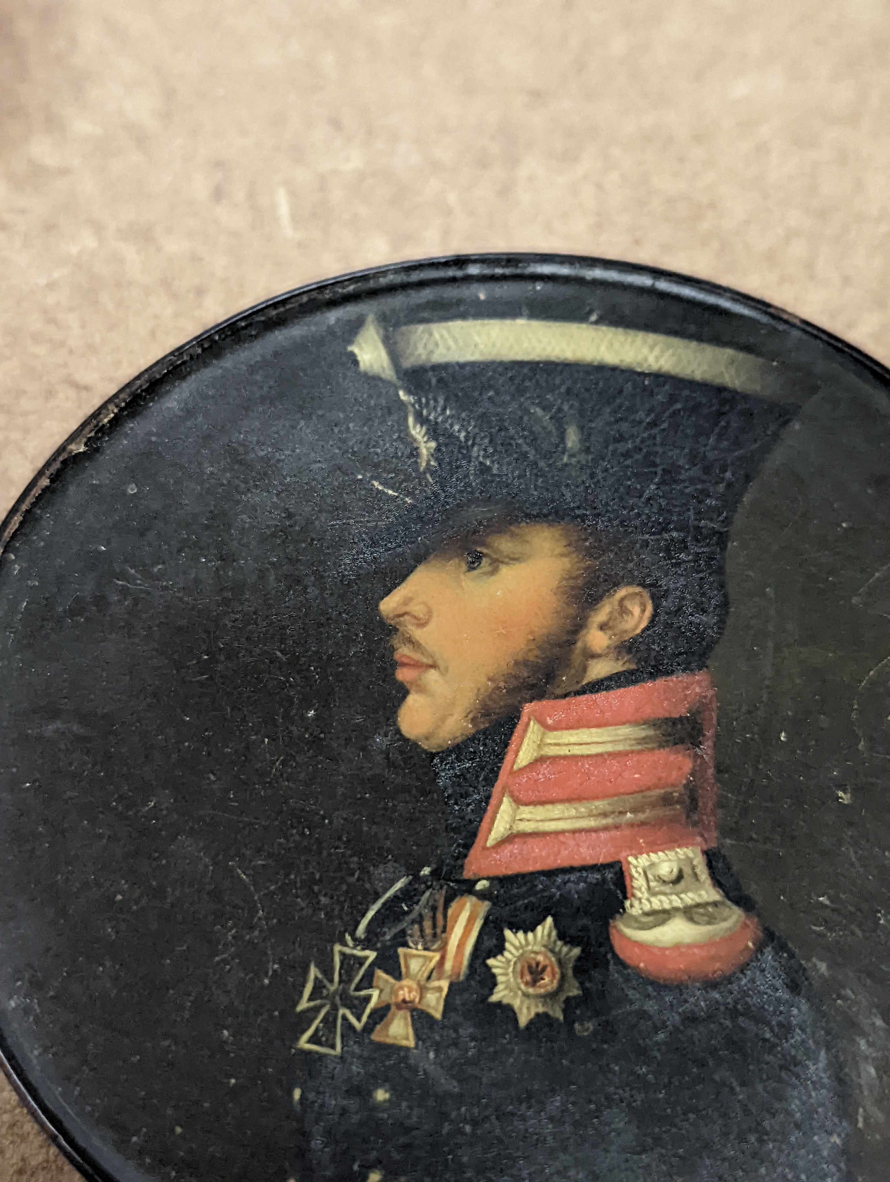 A 19th century Stobwasser papier mache ‘Henriette Sonntag’ portrait snuff box, c.1830, 9.7cm diameter and a 19th-century papier mache snuff box painted with a portrait of a German hussar, 9.4cm (2)